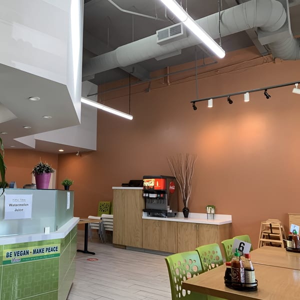 Interior of Green Lotus Restaurant with orange walls, light green chairs, and a drink dispenser.